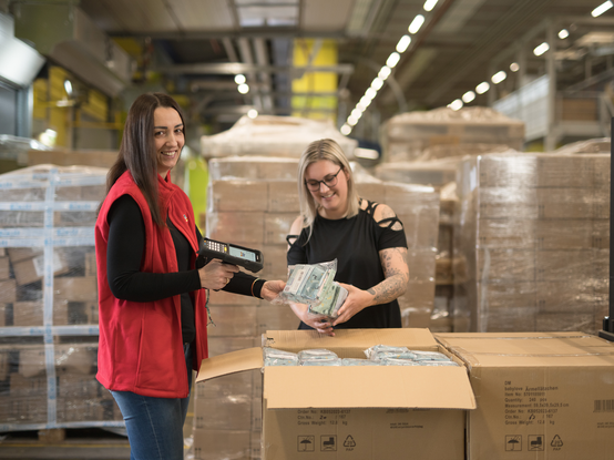 Колежки от логистичен център сканират продукти от доставка