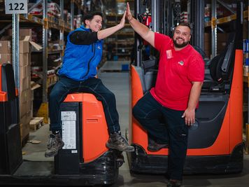 Двама колеги в склада, които карат високоповдигач.