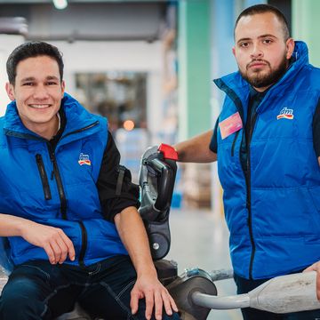 Двама колеги от логистичен център, усмихнати заедно.