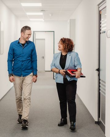 двама колеги вървят по коридор