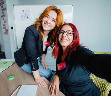 Две млади колежки си правят селфи в офиса