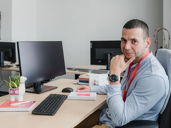 Колега от отдел администрация на Логистичен център dm е застанал на бюрото си и върши работа.